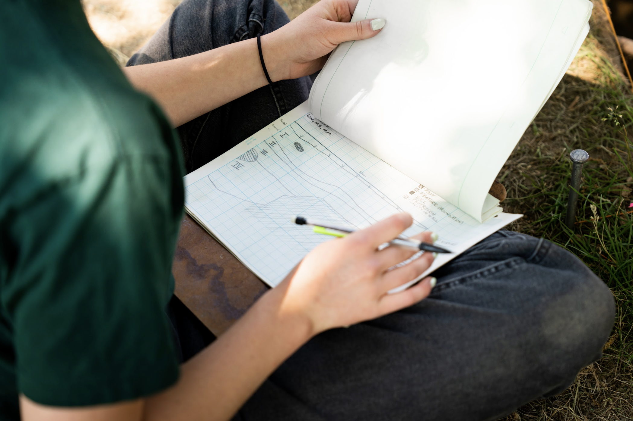 A person draws horizontal lines on grid paper.